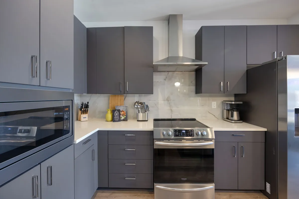 A stylish kitchen featuring stainless steel appliances, a marble backsplash, dark cabinetry, and a central island. The layout is designed for both functional meal preparation and hosting gatherings, with plenty of space for sharing recipes and celebrations.